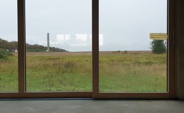 Blick durch Fensterfront nach draußen auf Grasland